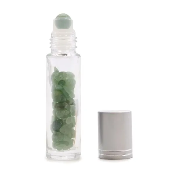 Glass essential oil roller bottle filled with green jade gemstones beside a silver cap.