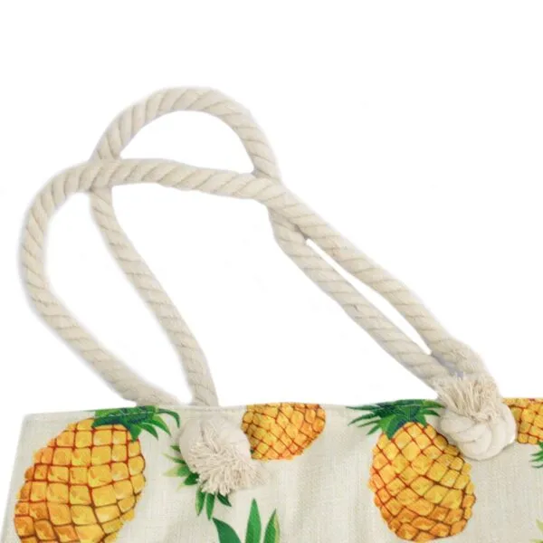 Off-white canvas tote bag featuring a tropical pineapple print and knotted jute handles.
