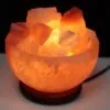 Glowing Himalayan salt bowl lamp filled with pink crystal chunks, emitting a warm glow.