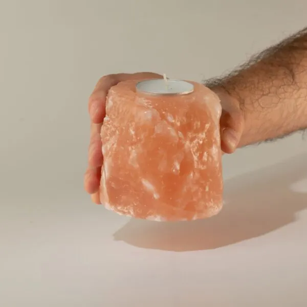 Tealight Candle Holder Himalayan Salt Pink Rough Cut A hand holding a rough-cut pink Himalayan salt tealight candle holder.