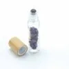 Clear glass essential oil roller bottle with purple amethyst crystals and bamboo caps.