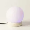 Sphere Table Lamp Himalayan Salt Purple Ambient Glow Glowing purple Himalayan salt sphere table lamp on a textured stone base.