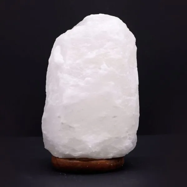 A glowing raw white salt crystal lamp mounted on a dark wooden base.