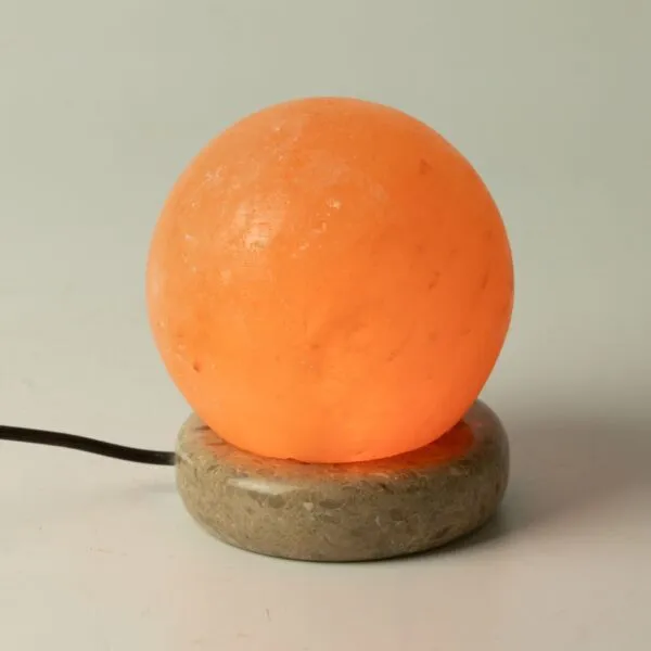 Himalayan Salt Lamp Spherical Natural Orange Stone Base Glowing spherical Himalayan salt lamp on a circular stone base emitting warm light.