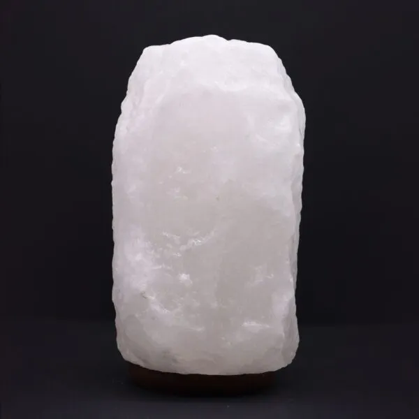 Himalayan Salt Lamp Rock Crystal White Dark Wooden Base Natural uncarved white Himalayan rock salt lamp standing on a dark wooden base.
