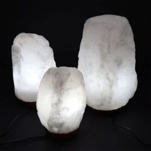 Himalayan Rock Salt Lamp Natural Crystal White Wooden Base Three glowing white Himalayan crystal salt lamps on wooden bases against a black background.