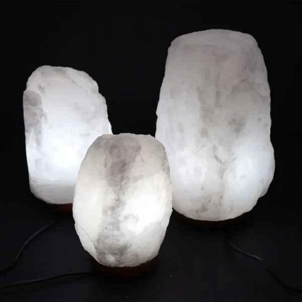 Himalayan Rock Salt Lamp Natural Crystal White Wooden Base Three glowing white Himalayan crystal salt lamps on wooden bases against a black background.