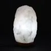 Glowing white Himalayan salt crystal lamp on a dark wooden base.