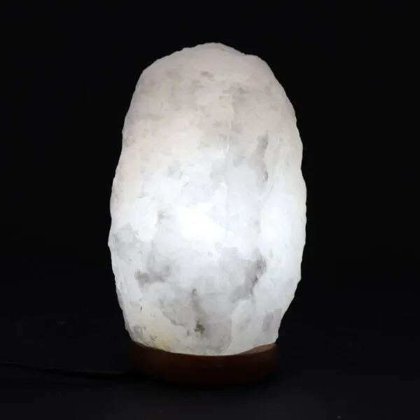 Glowing white Himalayan salt crystal lamp on a dark wooden base.