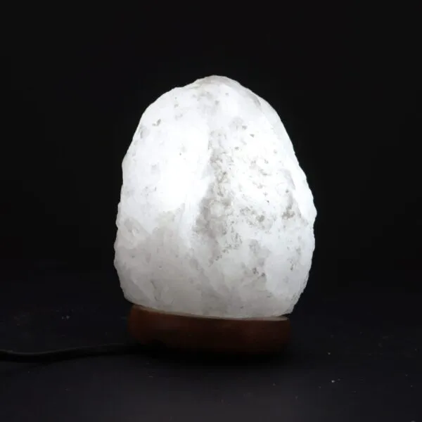 Glowing white Himalayan salt mountain lamp on a dark wooden base.