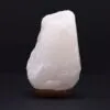 Raw natural white Himalayan salt rock lamp on a dark wooden base.