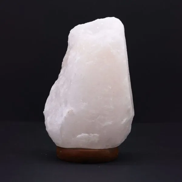 Raw natural white Himalayan salt rock lamp on a dark wooden base.