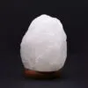 Natural white crystal rock salt lamp on a dark wooden base.