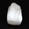 Illuminated natural white rock salt lamp glowing on a dark wooden base.