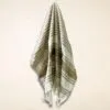 Folded brown and white striped woven cotton cloth with tassels and diamond pattern.