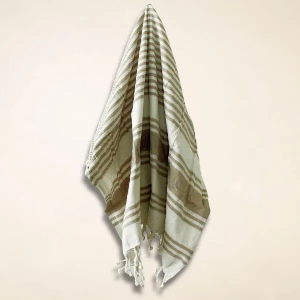 Folded brown and white striped woven cotton cloth with tassels and diamond pattern.