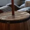 Wooden Barrel Table Reclaimed Oak Brown Central Pole Hole Reclaimed oak wooden barrel table with parasol hole, set in a cosy rustic lounge.