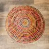 Round multicoloured braided jute area rug with a vibrant spiral pattern on wooden flooring.