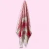 Red and white striped Turkish cotton peshtemal towel with fringes hanging from a hook.
