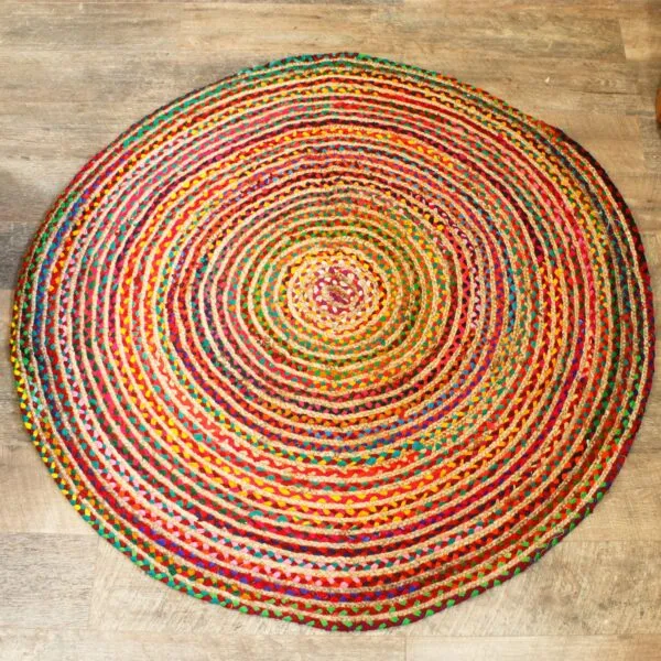 Round red braided yarn rug with a multicoloured spiral pattern on light wood floorboards.