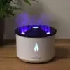 White essential oil diffuser producing a colourful cool flame mist on a wooden table.